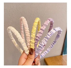 Detailed macro view of pleated satin headbands in a variety of soft pastel colors