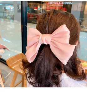 Detalle de lazo rosa de satén en cabello largo ondulado con un acabado nacarado