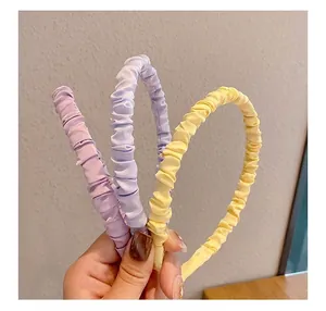 Close-up of pleated satin headbands in light purple, sky blue, and pastel yellow colors