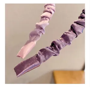 Macro shot of satin pleated headband showing smooth texture and elegant purple fabric folds