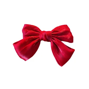 Elegante pinza de pelo con lazo grande de satén rojo y textura metalizada brillante