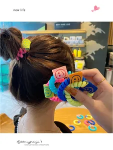 Dettaglio di elastici a spirale colorati con etichette smiley indossati su una coda