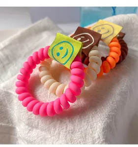 Dettaglio di elastici a spirale colorati con etichette tessute a faccina sorridente