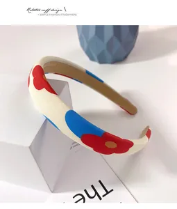Détail d'un serre-tête floral en tissu avec fleurs bleues et rouges sur base crème