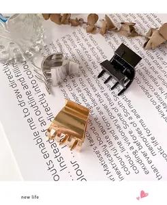 Drei minimalistische Haarklammern aus Metall in Gold, Silber und Schwarz auf Papierhintergrund