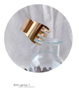 Detail einer eleganten goldenen Haarklammer aus Metall an einer Glasvase präsentiert