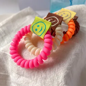 Set di quattro elastici per capelli a spirale colorati con etichette smiley su tessuto