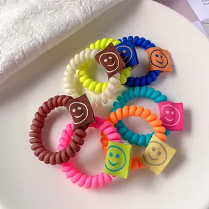 Set di elastici per capelli a spirale colorati con etichette smiley in un piatto