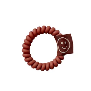 Elastico per capelli a spirale marrone rossastro opaco con etichetta smiley