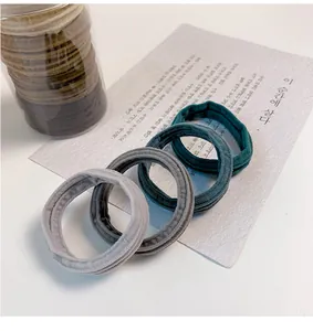 Close-up of seamless nylon elastic hair ties in earthy tones with clear storage tube
