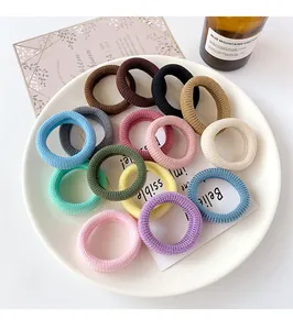 Detailed close-up of 14 colorful seamless elastic hair ties with woven texture in a tray