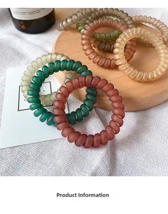 Close-up of matte spiral telephone wire hair ties in various earthy colors on a wooden tray