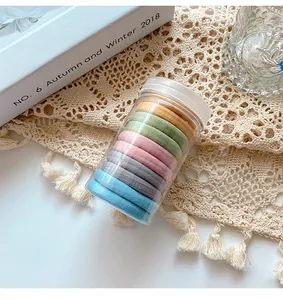 Close-up of colorful seamless hair ties in a clear storage jar on a lace tablecloth