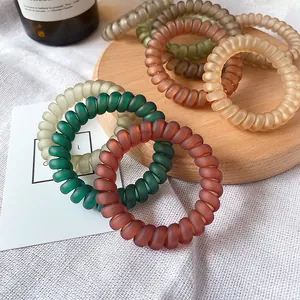 Matte telephone cord hair ties in Morandi colors displayed on wooden tray and linen cloth