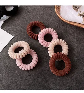 Dettaglio di cinque elastici per capelli in velluto a spirale in toni marrone e beige