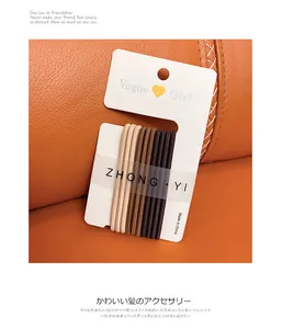 Close-up of five earth-toned high elastic hair ties on a Vogue Girl display card