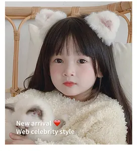 Detail of white faux fur cat ear hair clips worn by a girl in a cozy home setting