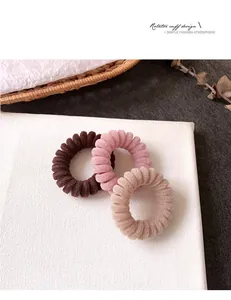 Dettaglio di elastici per capelli a spirale floccati in marrone, rosa e kaki su fondo bianco