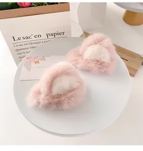 Detailed close-up of fluffy pink faux fur cat ear hair clips on a white display tray