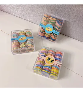 Tres paquetes de gomas elásticas de colores para bebé en cajas transparentes