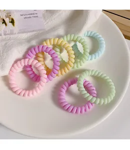 Set of nine colorful spiral telephone cord hair ties in pastel macaron shades on a tray