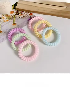Five matte macabre telephone wire hair ties in pastel colors on a rustic wooden board