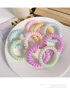 Macro shot of colorful spiral telephone wire hair ties arranged in a white ceramic dish