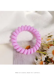 Detailed macro view of a matte light pink spiral hair tie on white fabric background