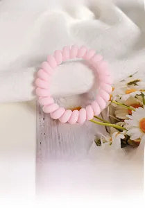 Pink frosted spiral telephone cord hair tie shown on elegant white fabric with daisies