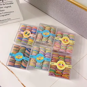 Coleteros elásticos de colores para niños en seis cajas sobre fondo de mármol