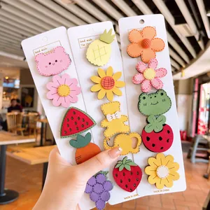 Close-up of 14 colorful cartoon animal and fruit fabric hair pins on white display card