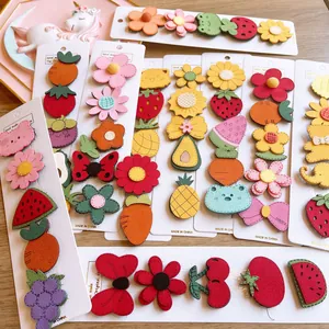 Flat lay of colorful cartoon fruit and animal velcro hair clips for girls on wood table