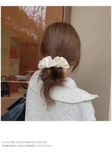 Détail d'un chouchou géant en satin beige sur un chignon bas élégant au soleil