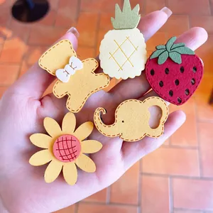 Detail of five cute fabric hair clips featuring bear, pineapple, and strawberry designs