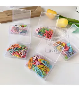 Close-up of colorful polka dot metal hair clips in transparent storage boxes with floral decor