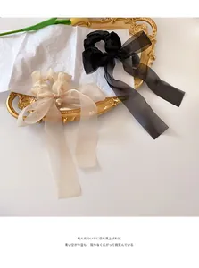 Detail of elegant organza bow scrunchies in black and champagne on a vintage tray