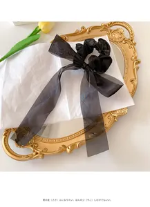 Close-up of black organza scrunchie with long ribbon bow on elegant vintage background