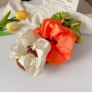 Trois chouchous en satin de qualité en crème, orange et vert olive pour un style élégant