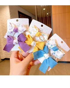 Detail of three pairs of knitted bow hair clips in purple, yellow and blue for children