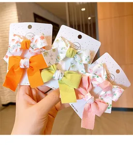Three pairs of handmade knit bow hair clips in orange, green, and pink floral patterns