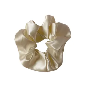 Chouchou élégant en satin champagne avec plis soyeux sur fond blanc impeccable