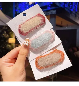 Detailed view of three plush wool bow hair clips for kids on a display card