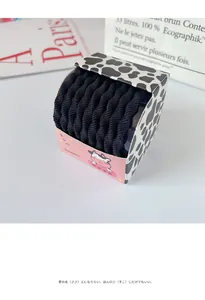 Détail d'élastiques à cheveux noirs dans une boîte rose avec motif de vache