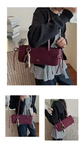 Detail of burgundy matte baguette bag with beaded charm and ribbon on side