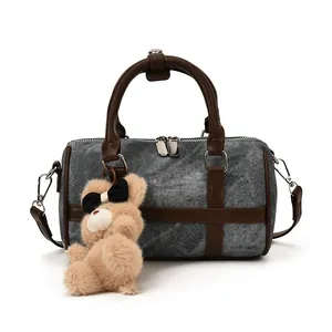 Bolso cilíndrico de mezclilla con asas de cuero marrón y colgante de osito de peluche