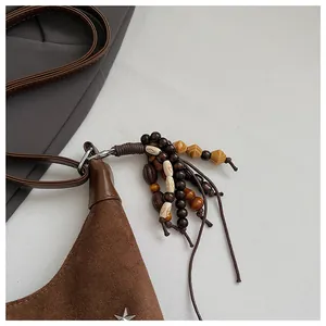 Détail du sac seau en daim marron avec pampille en perles et étoile en métal argenté