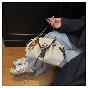 Détail du sac bandoulière en toile crème avec bordure en cuir marron et perle en bois