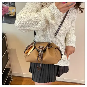Sac seau vintage en toile marron porté épaule avec sangle en cuir et perles colorées