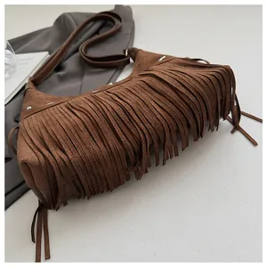 Détails d'un sac seau en daim marron à franges avec clous argentés style bohème