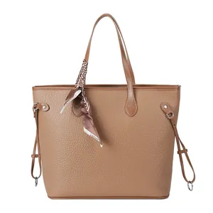 Brown litchi leather tote bag with a patterned silk scarf on the handle, white background